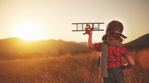 happy child dreams of traveling and playing with an airplane pilot aviator in outdoor in the summer